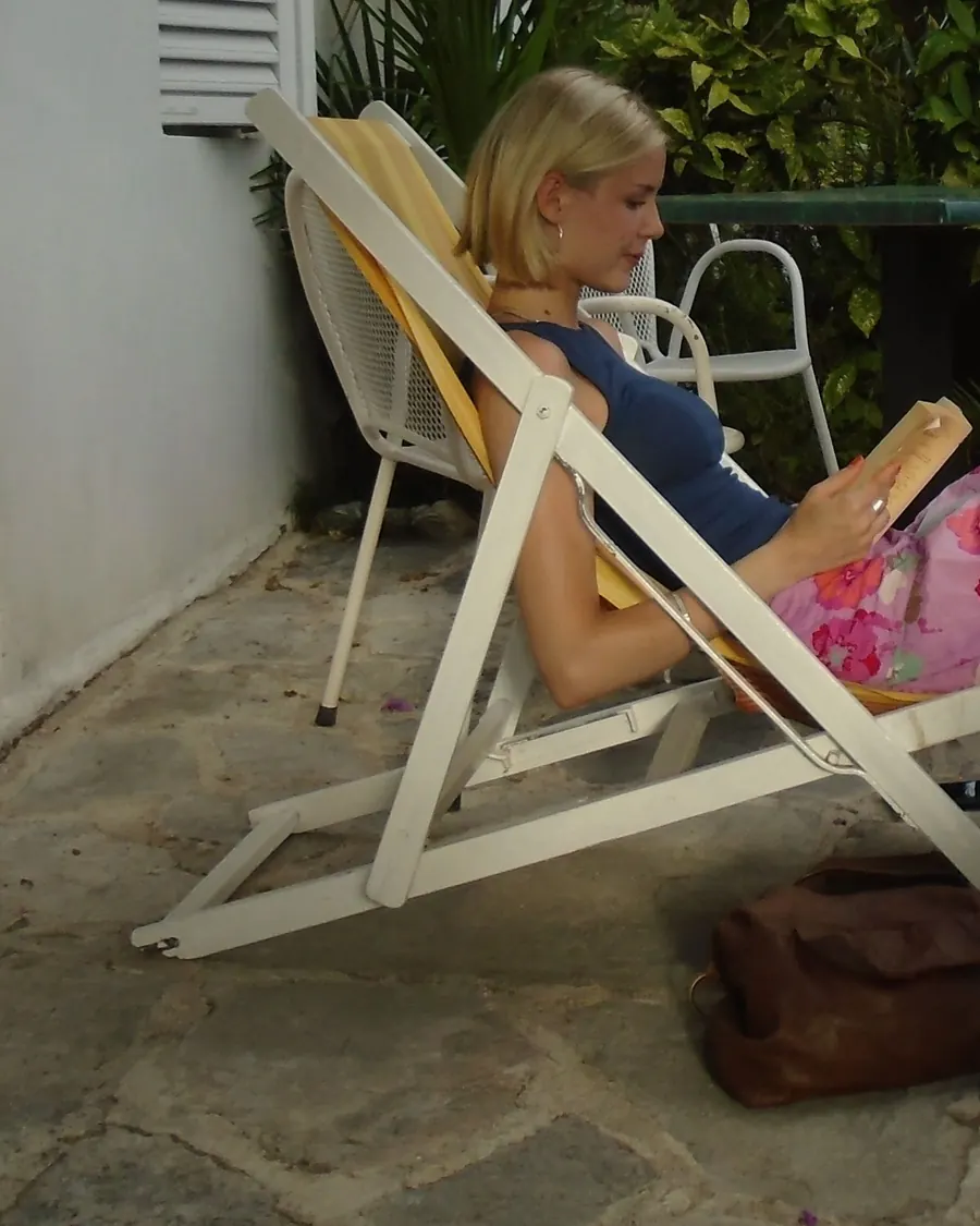 Martha Perry reading in a deckchair in a leafy, sunny garden