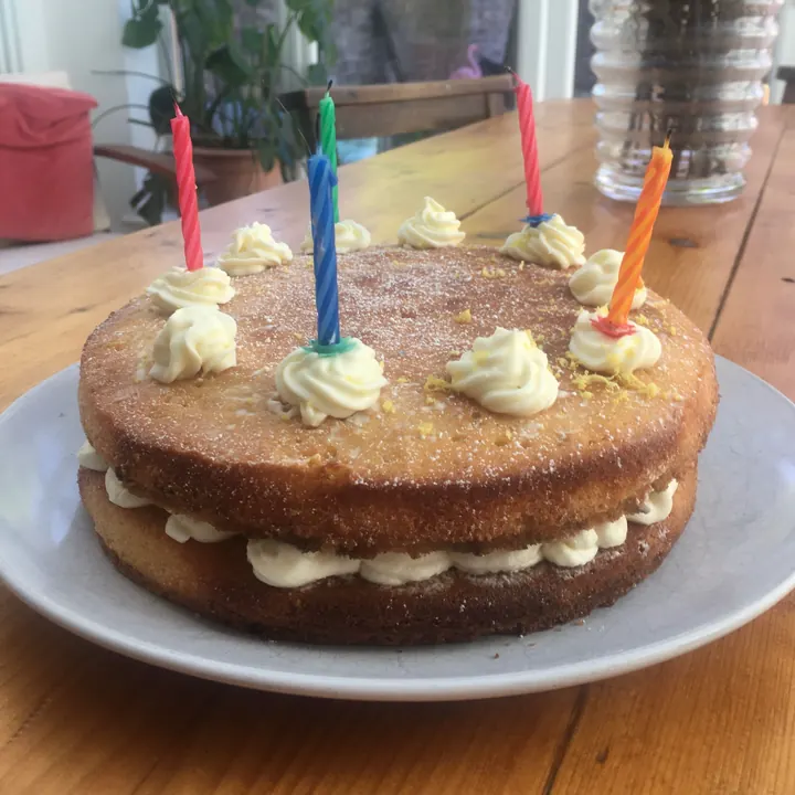 Birthday sponge cake with cream rosettes and coloured candles
