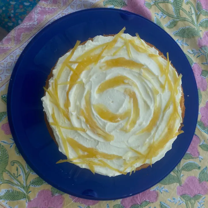 Lemon curd layer cake topped with lemon zest on a blue plate