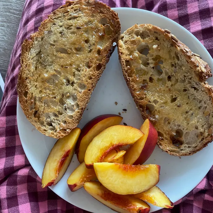 Buttered sourdough toast with slices of fresh peach
