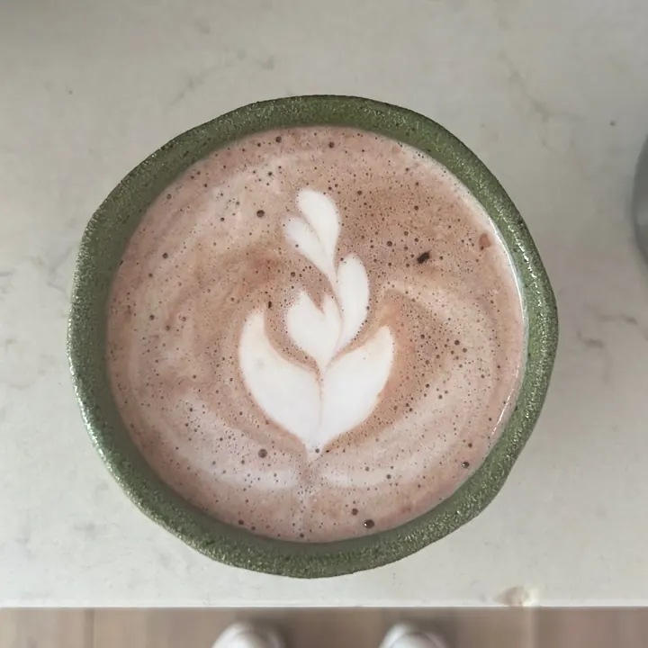 Hot chocolate with tulip latte art in a green cup