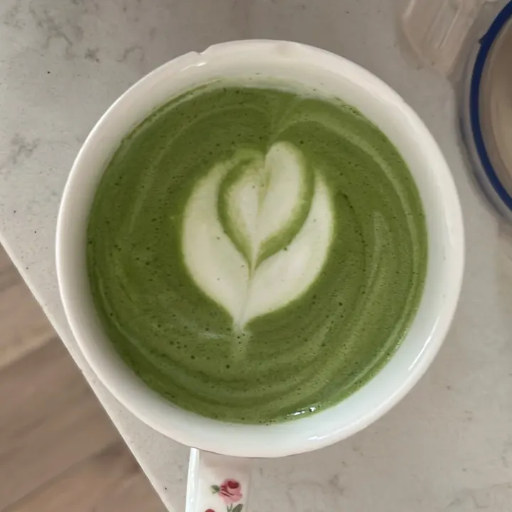 Matcha latte with tulip latte art in a white cup