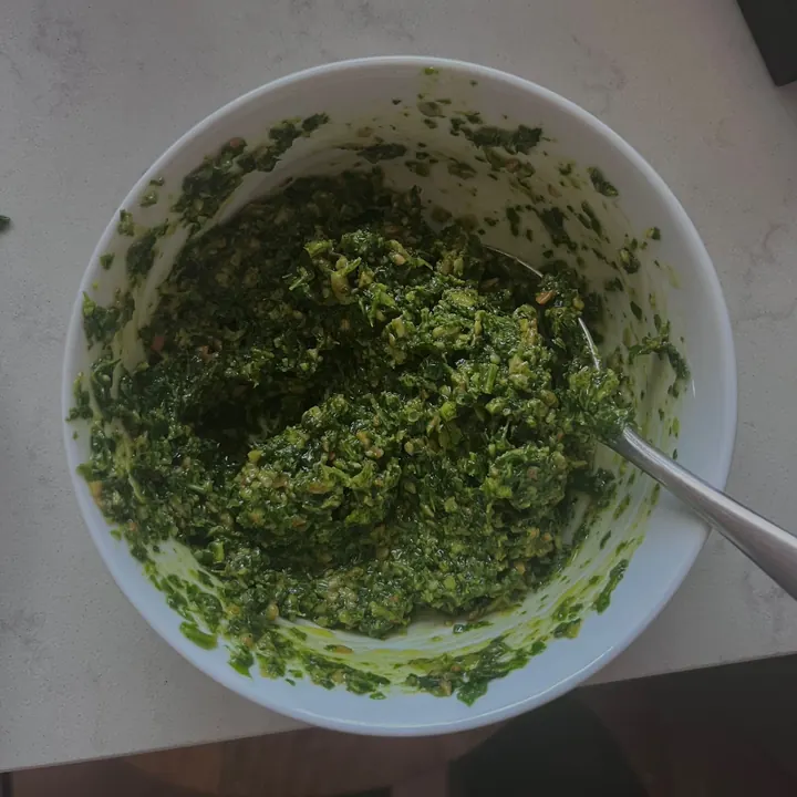 Bowl of bright green rocket pesto with a spoon