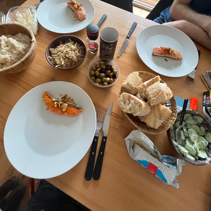 A shared table in Paris with salmon, bread, olives and salads